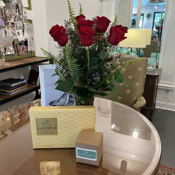Bouquet of red roses in a glass vase with chocolates on a table