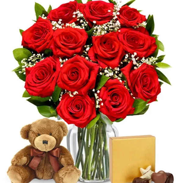 Bouquet of red roses in a glass vase with a teddy bear and chocolates
