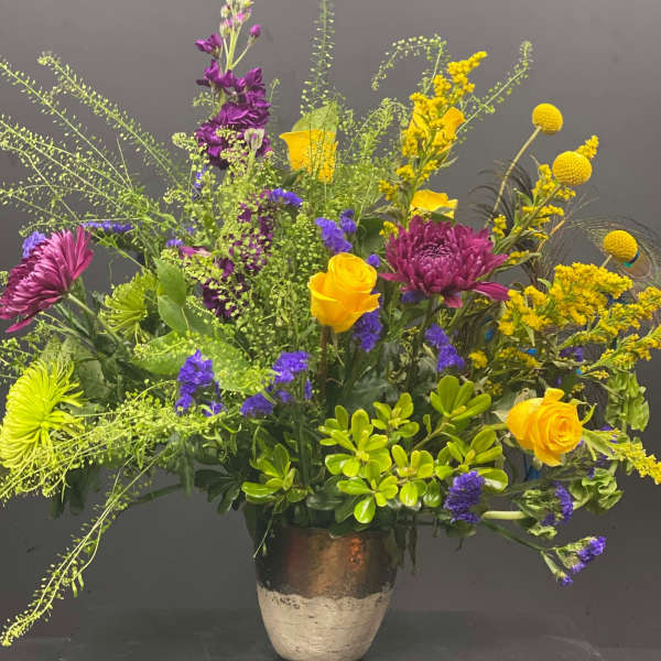 Mixed bouquet of yellow, purple, and pink flowers in a ceramic vase