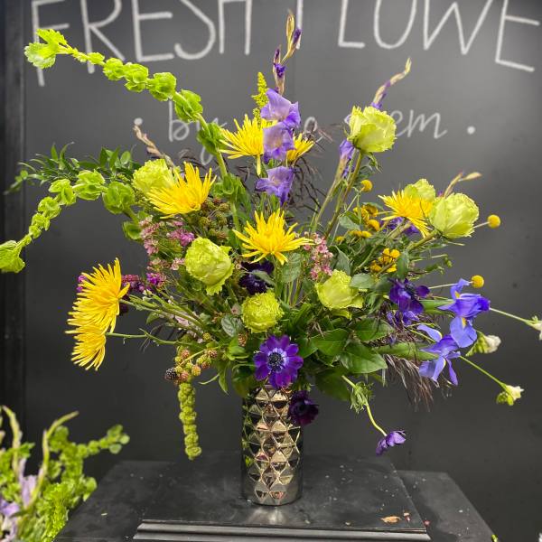 Tall mixed bouquet in a metallic vase with yellow, purple, and green flowers