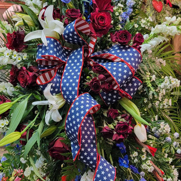 Large floral standing spray with red, white, and blue flowers and an American flag ribbon