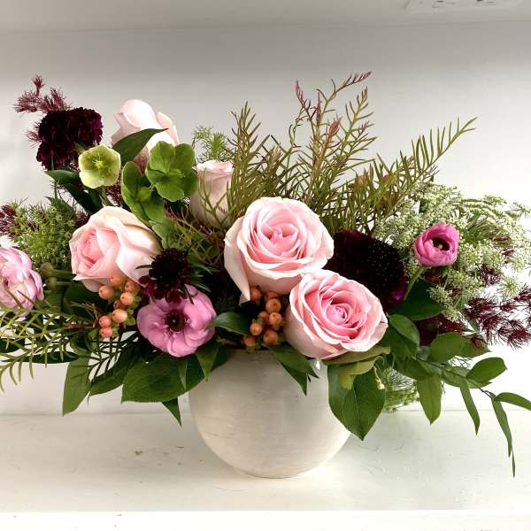 Pink roses and mixed flowers arranged in a white vase
