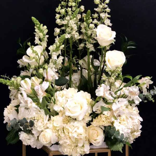 White floral arrangement with roses, hydrangeas, and tall snapdragons