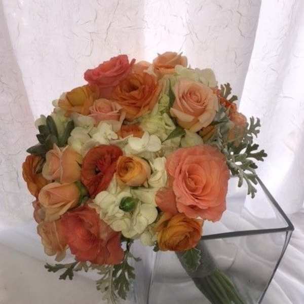 Bouquet of peach and orange roses in a clear square vase