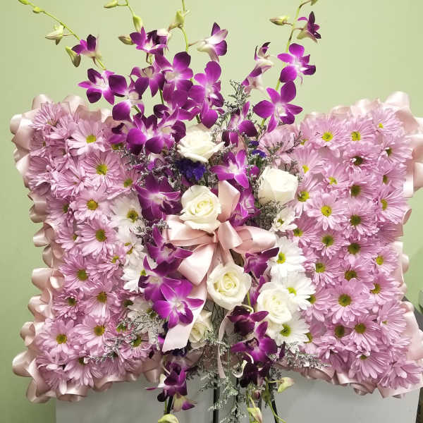 Pink and purple floral standing arrangement with white roses on an easel