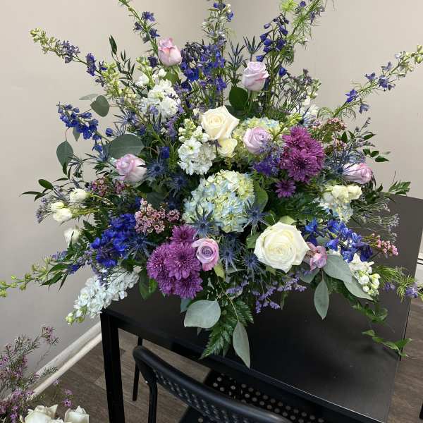 Large mixed floral arrangement with roses, hydrangeas, and purple blooms