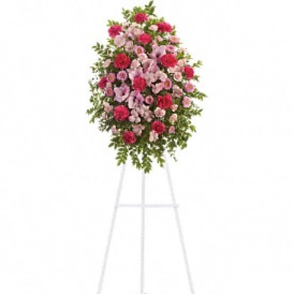 Standing floral spray of pink and red flowers on a white easel