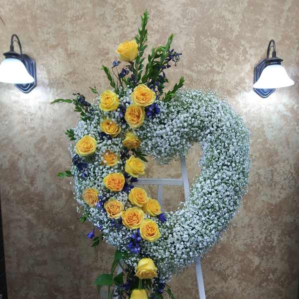 Yellow roses and white baby's breath arranged on a standing wreath