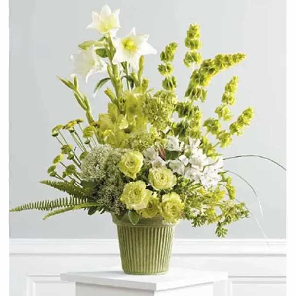 Green and white floral arrangement in a ribbed green vase