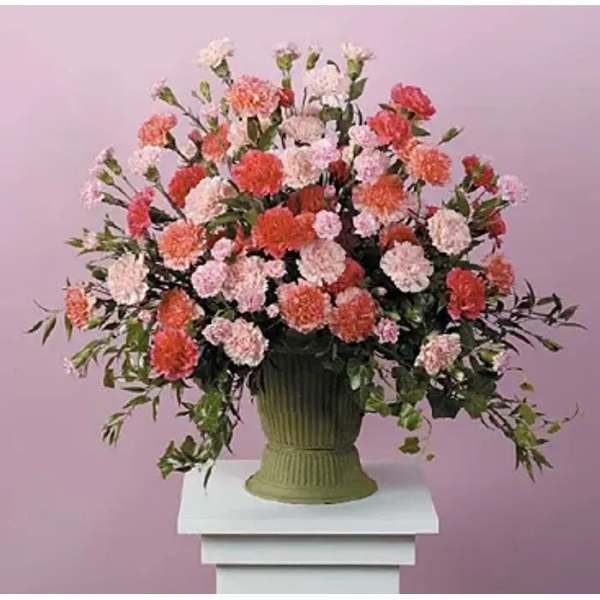 Large arrangement of pink and coral carnations in a green vase