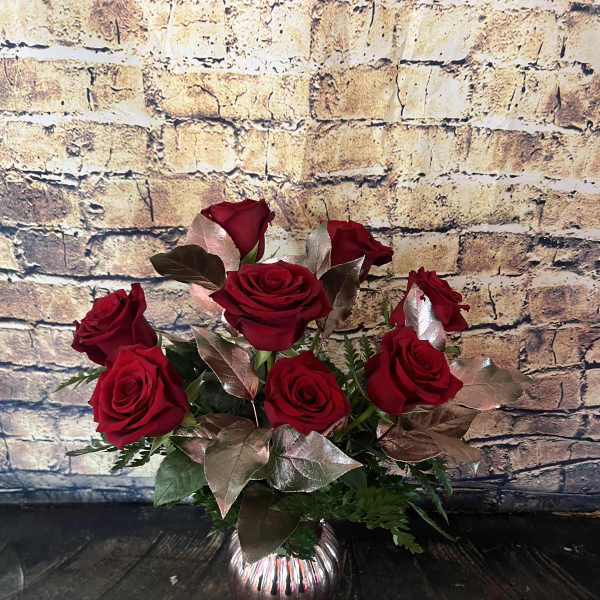 Red roses arranged in a small glass vase