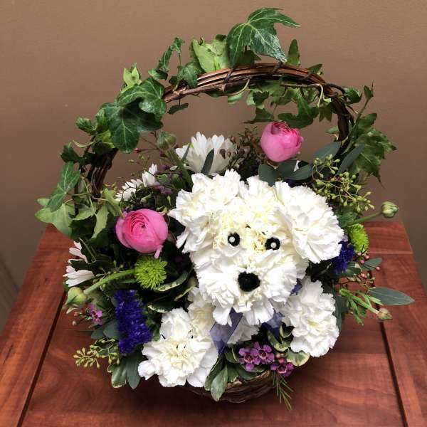 White flower arrangement in a wicker basket shaped like a dog