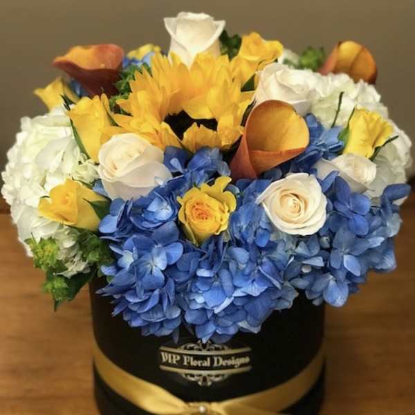 Mixed bouquet of blue hydrangeas, yellow sunflowers, white roses, and orange calla lilies in a black box