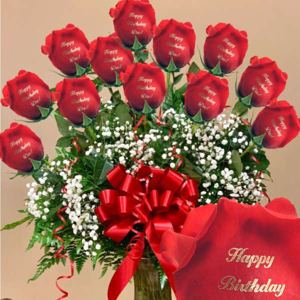 Red roses in a glass vase with a birthday ribbon and card