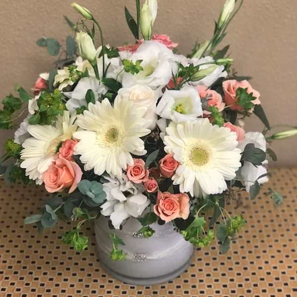 Bouquet of white gerbera daisies and peach roses in a gray vase