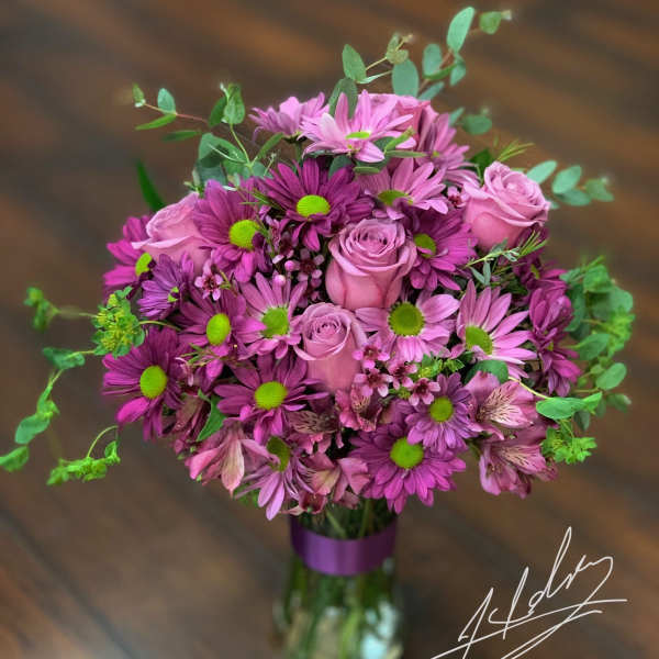 Pink and purple bouquet of roses and daisies in a glass vase