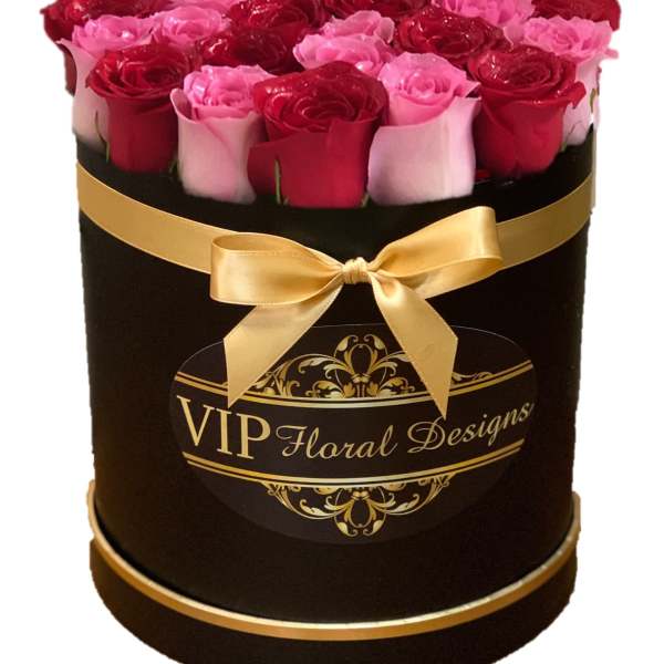 Round box of red and pink roses with a gold ribbon