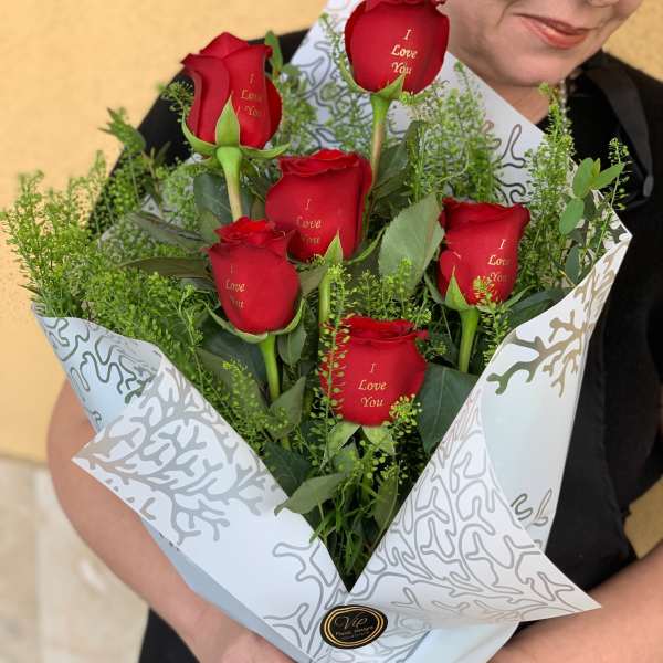 Bouquet of red roses wrapped in white paper with a black ribbon