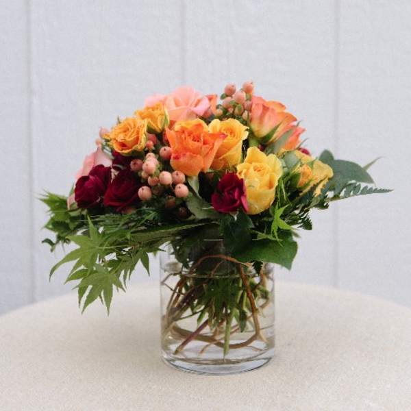Mixed roses in a clear glass vase with greenery