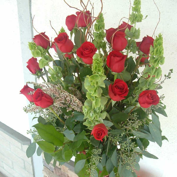 Tall bouquet of red roses with green filler in a decorative vase
