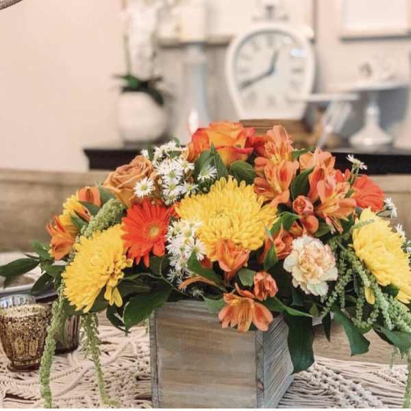 Orange and yellow floral arrangement in a wooden box centerpiece