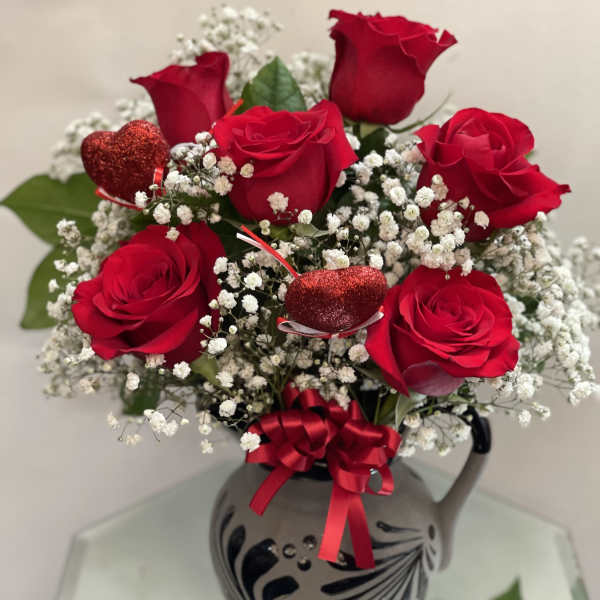 Red roses with baby's breath in a decorative vase and ribbon