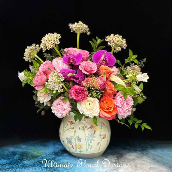 Mixed pink and purple flowers arranged in a painted ceramic vase
