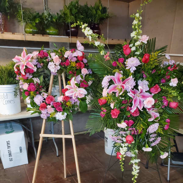 Two large floral wreaths on stands with pink lilies and roses