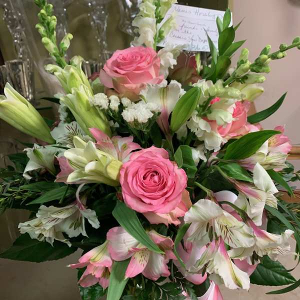 Pink roses and white lilies arranged with pink alstroemeria in a bouquet