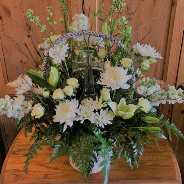 White floral arrangement with a glass cross in a basket