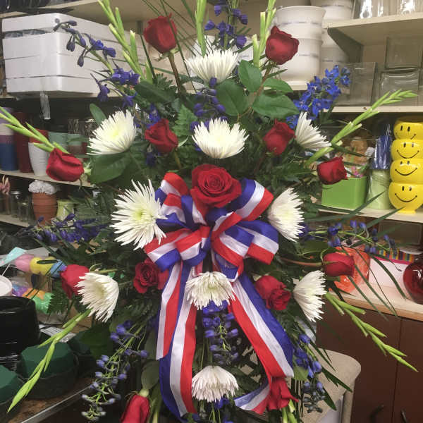 Large red, white, and blue floral standing spray with roses and ribbon