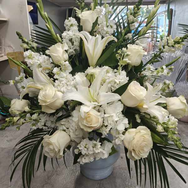 Large white floral arrangement in a gray vase with roses and lilies