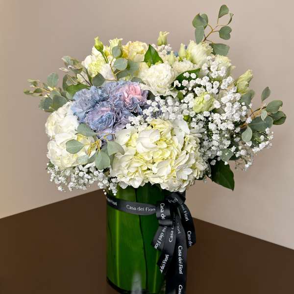 Bouquet of white and pale blue flowers in a green glass vase