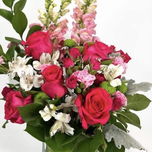 Pink roses and mixed blooms arranged in a clear glass vase