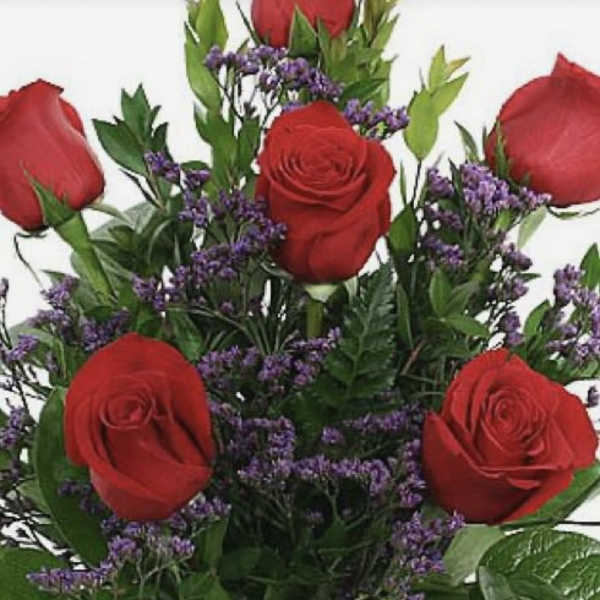 Bouquet of red roses and purple filler flowers in a clear glass vase
