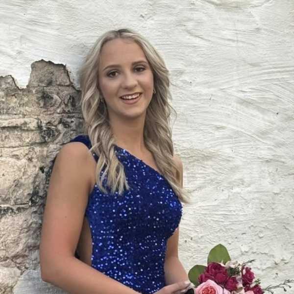 Woman in a blue dress holding a pink rose bouquet