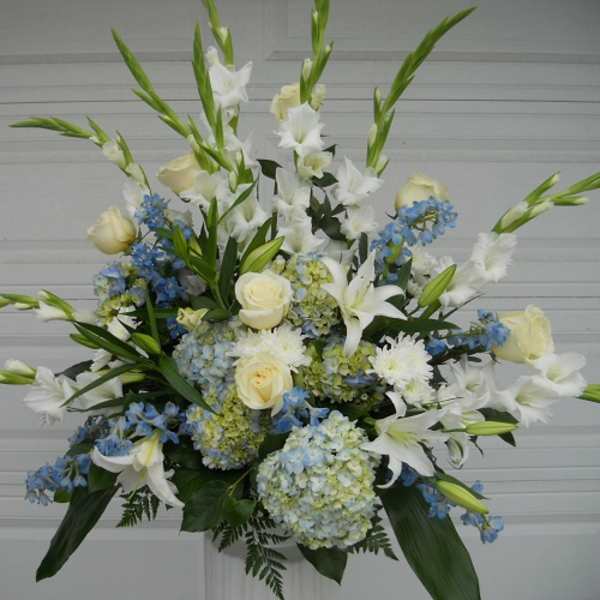 Tall white and blue floral arrangement with roses and lilies