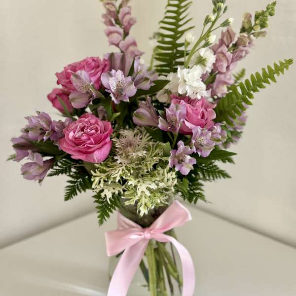 Pink and lavender bouquet in a glass vase with a pink ribbon