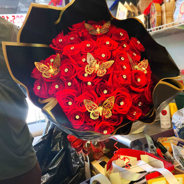 Bouquet of red roses with gold butterfly decorations in black wrap