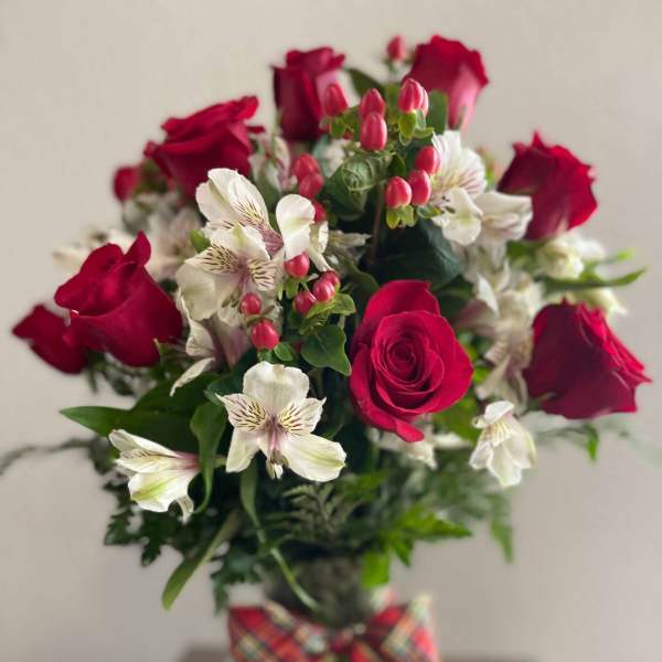 Bouquet of red roses and white alstroemeria in a glass vase with plaid ribbon