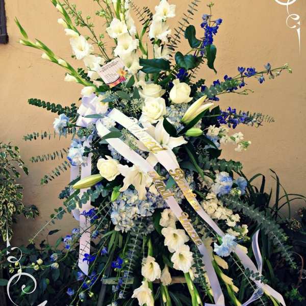 Tall white floral spray with blue accents and ribbon streamers