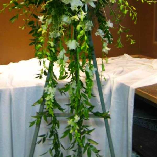 Tall white floral spray on a stand with cascading greenery