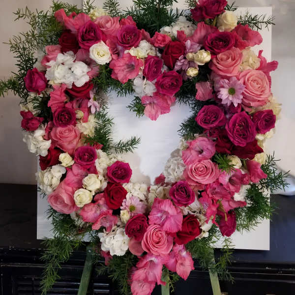 Heart-shaped floral wreath of pink and white roses with greenery