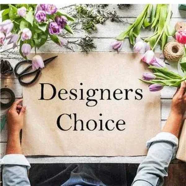 Hands hold a Designers Choice sign on a table surrounded by loose pink and purple tulip stems and tools.
