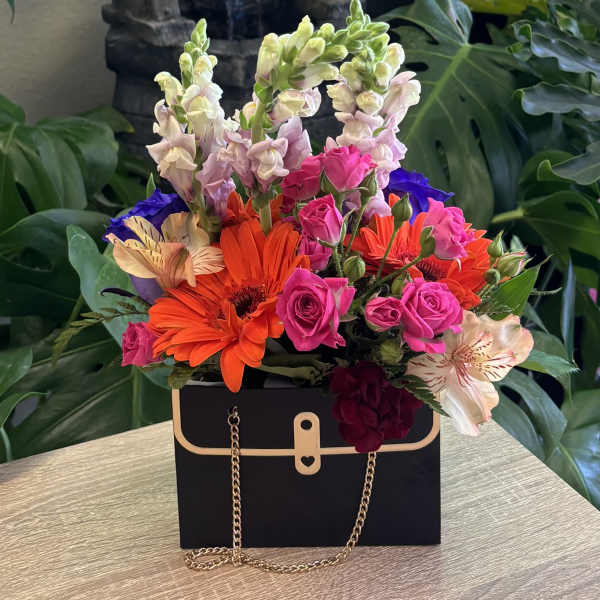 Bright mixed bouquet in a black handbag-style box with gold chain handles