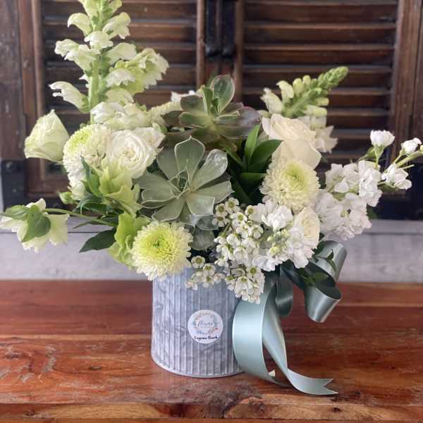 White floral arrangement in a silver tin with a blue ribbon