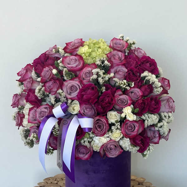 Large bouquet of pink and purple roses in a purple box with ribbon
