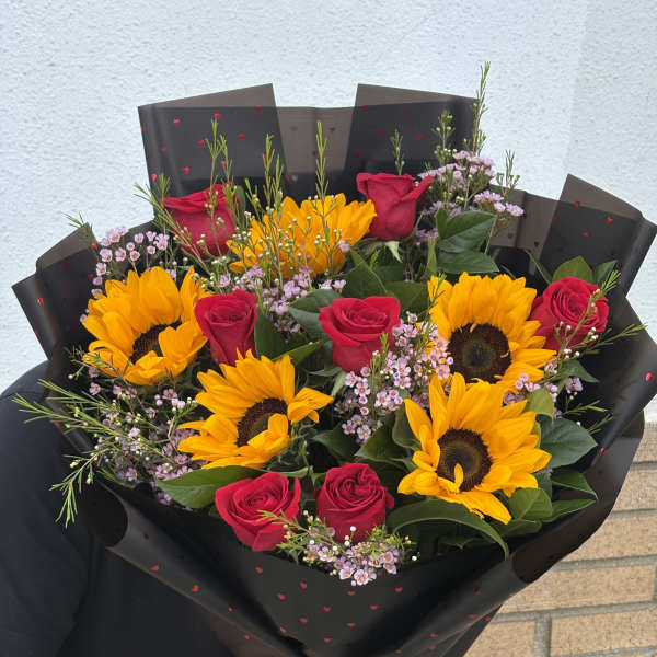 Bouquet of red roses and sunflowers wrapped in black paper