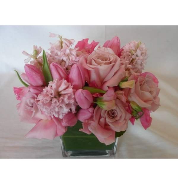 Pink roses and tulips arranged in a square glass vase