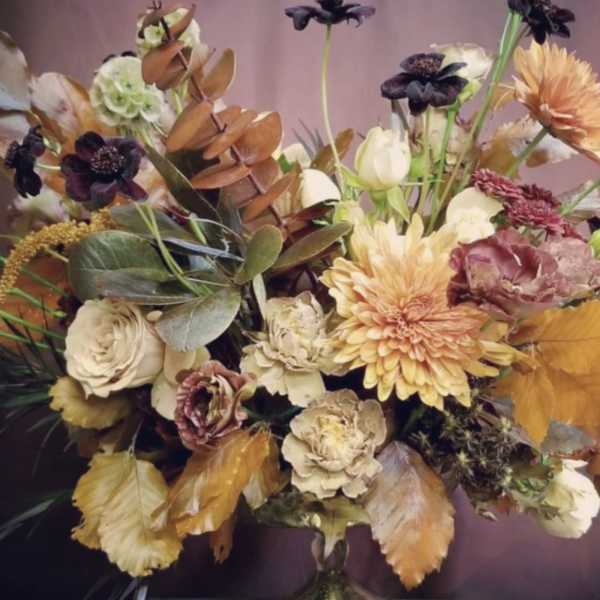 Mixed bouquet in a glass vase with peach, cream, and dark purple blooms
